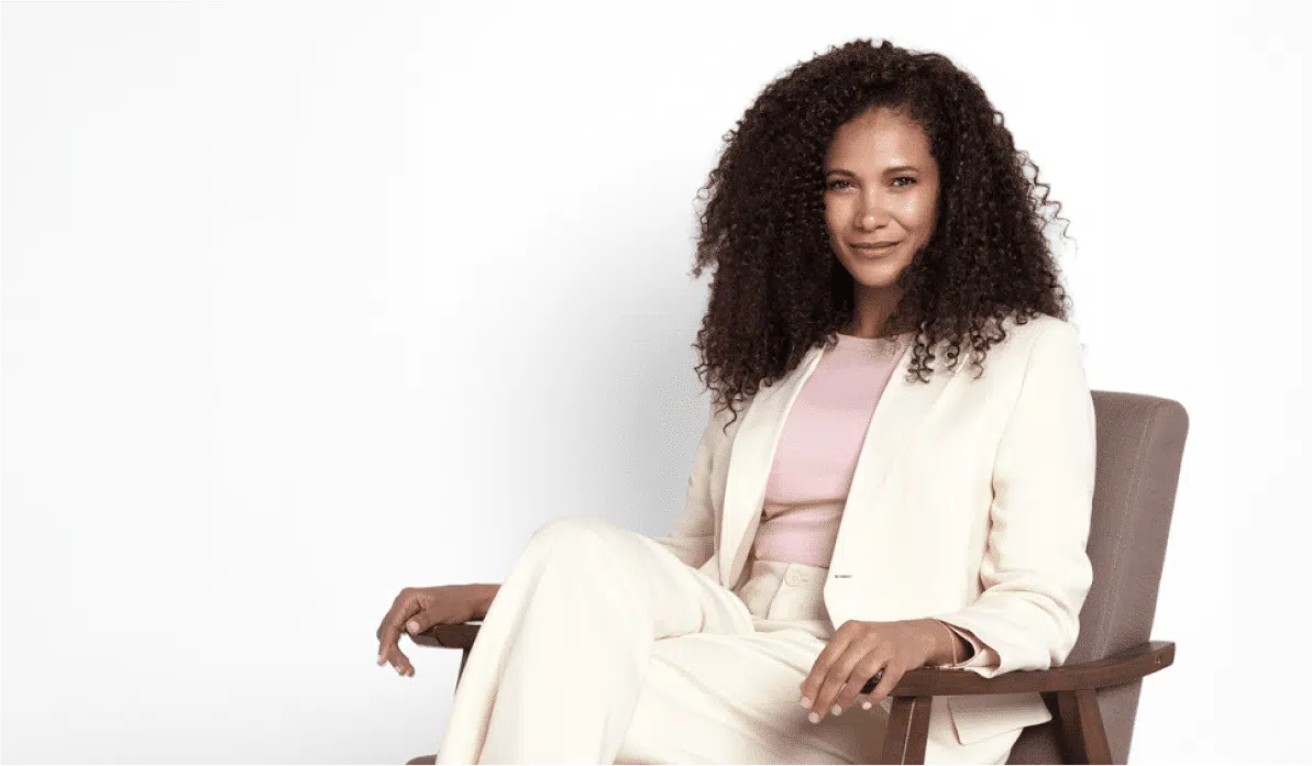 Young professional woman sitting with her legs crossed looking confidently at the camera