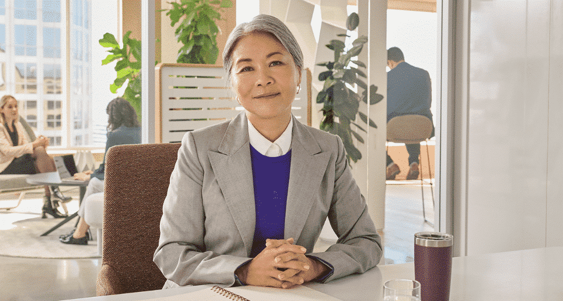 Female leader sitting at her desk with hands crossed looking at the camera compassionately