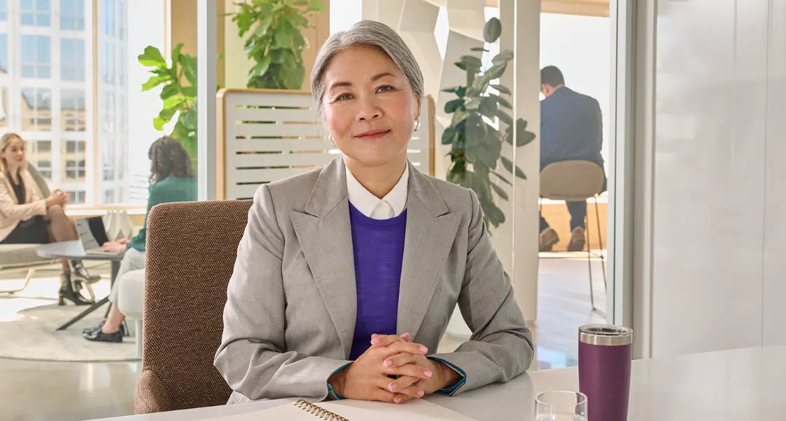 Female leader sitting at her desk with hands crossed looking at the camera compassionately
