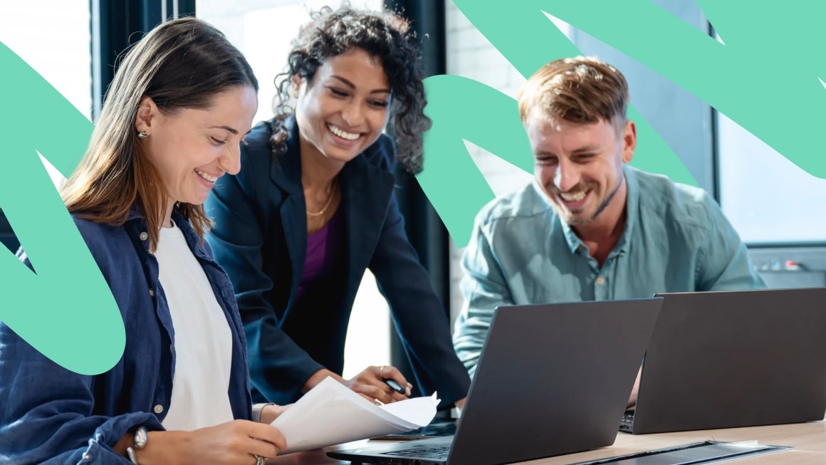 Three coworkers smiling and collaborating on work
