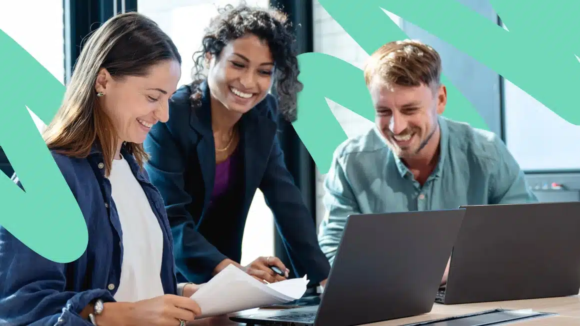 Three coworkers smiling and collaborating on work