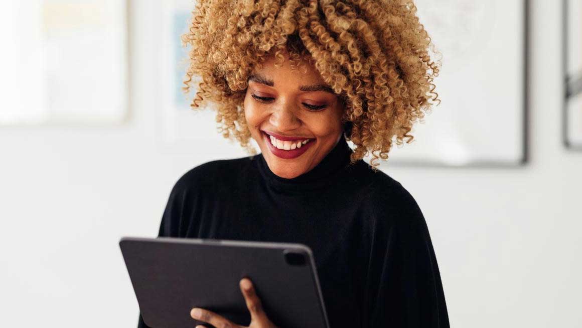 Smiling woman in black turtle neck looking down at her tablet